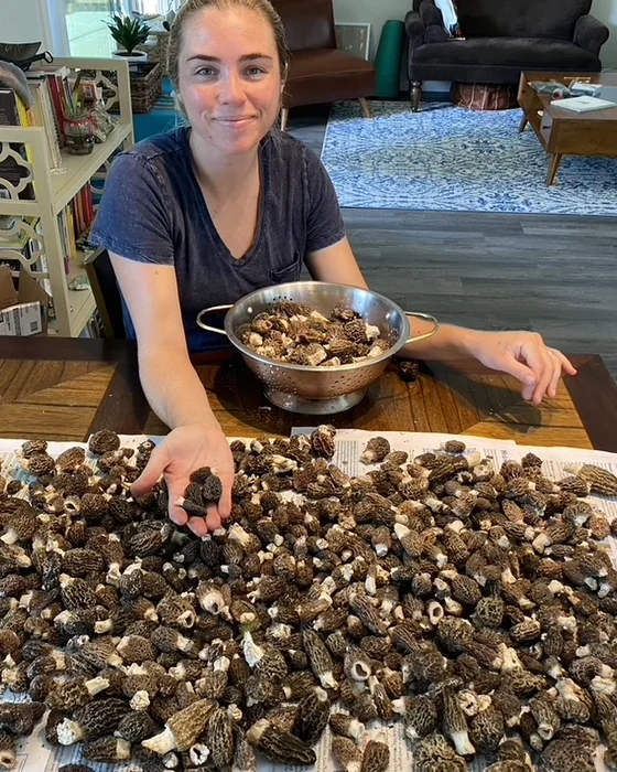 Louisa Disheroon at a table covered with a large harvest of morel mushrooms